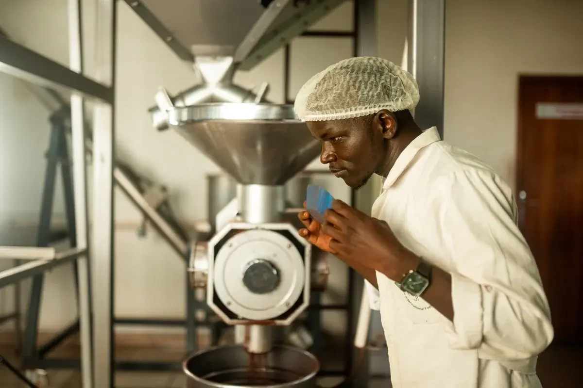 A young man roasting coffee wearing protective outfit for food manufacturing, in Uganda for CURAD Incubation Hub
